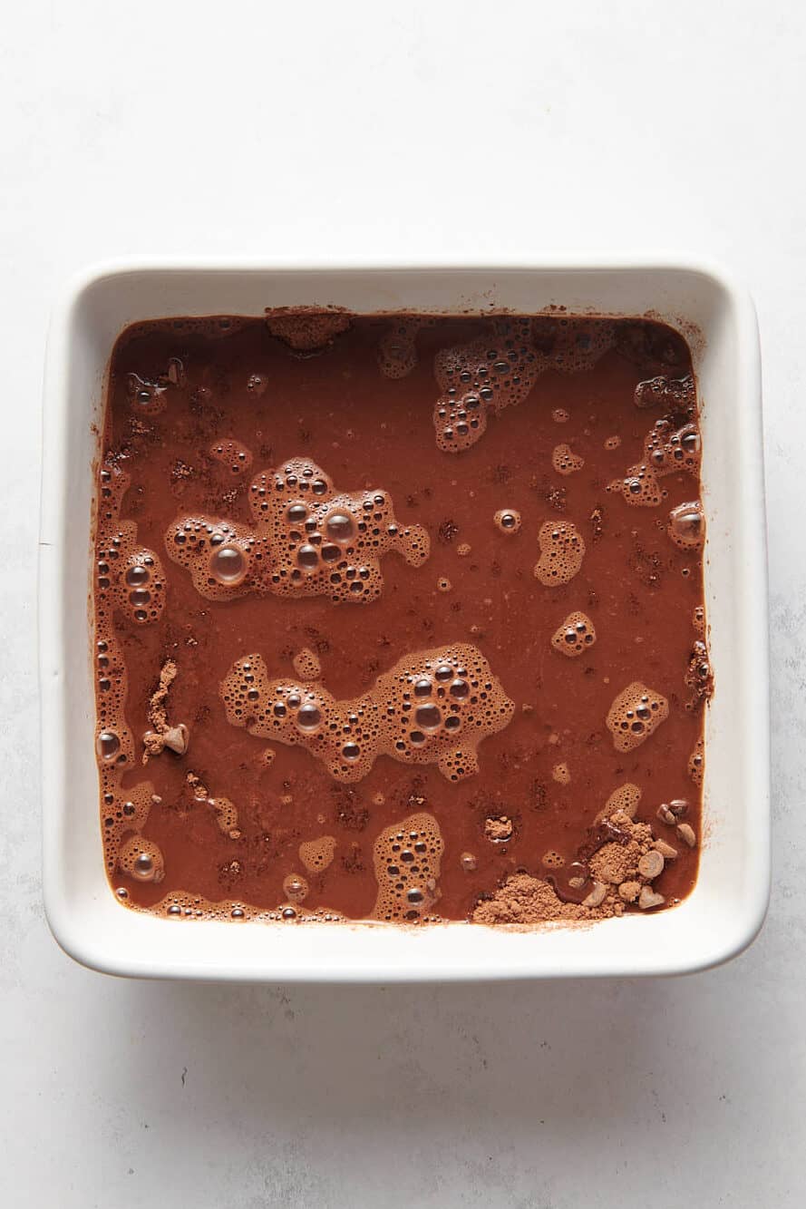 chocolate pudding cake batter topped with hot water prepped in an 8x8 baking dish.