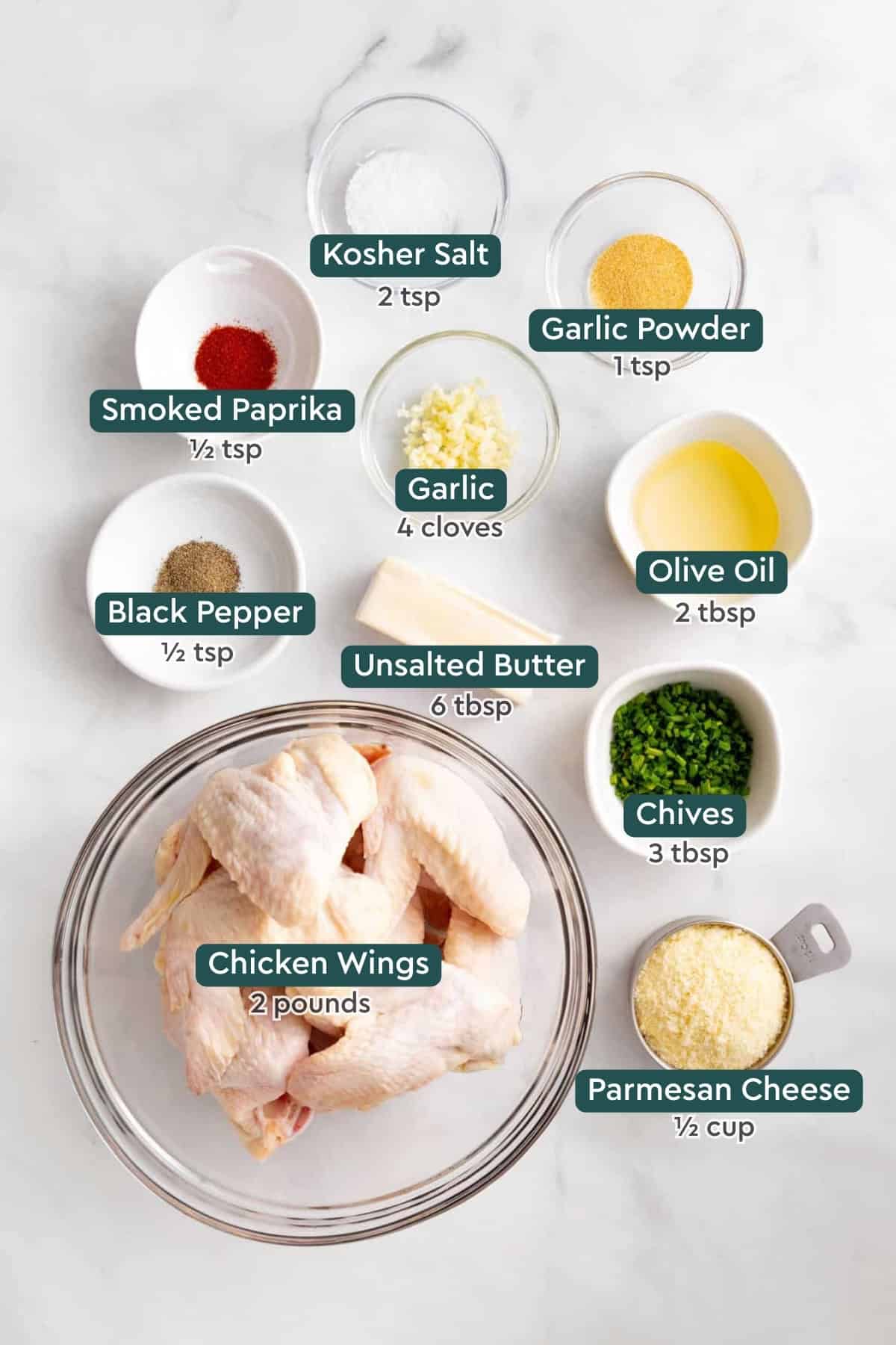 Ingredients for garlic parmesan wings, including salt, garlic powder, paprika, garlic, oil, pepper, butter, chives, chicken, parmesan.