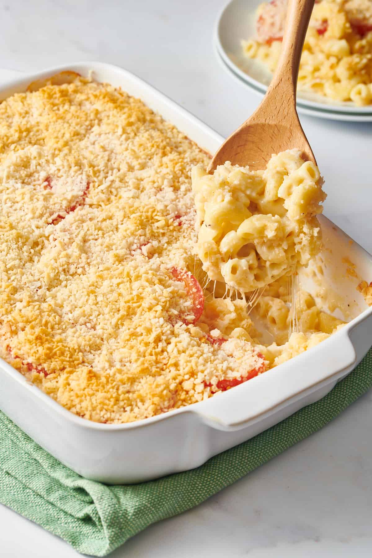 9x13 casserole dish with ina garten mac and cheese and a wooden spoonful of the mac and cheese. 