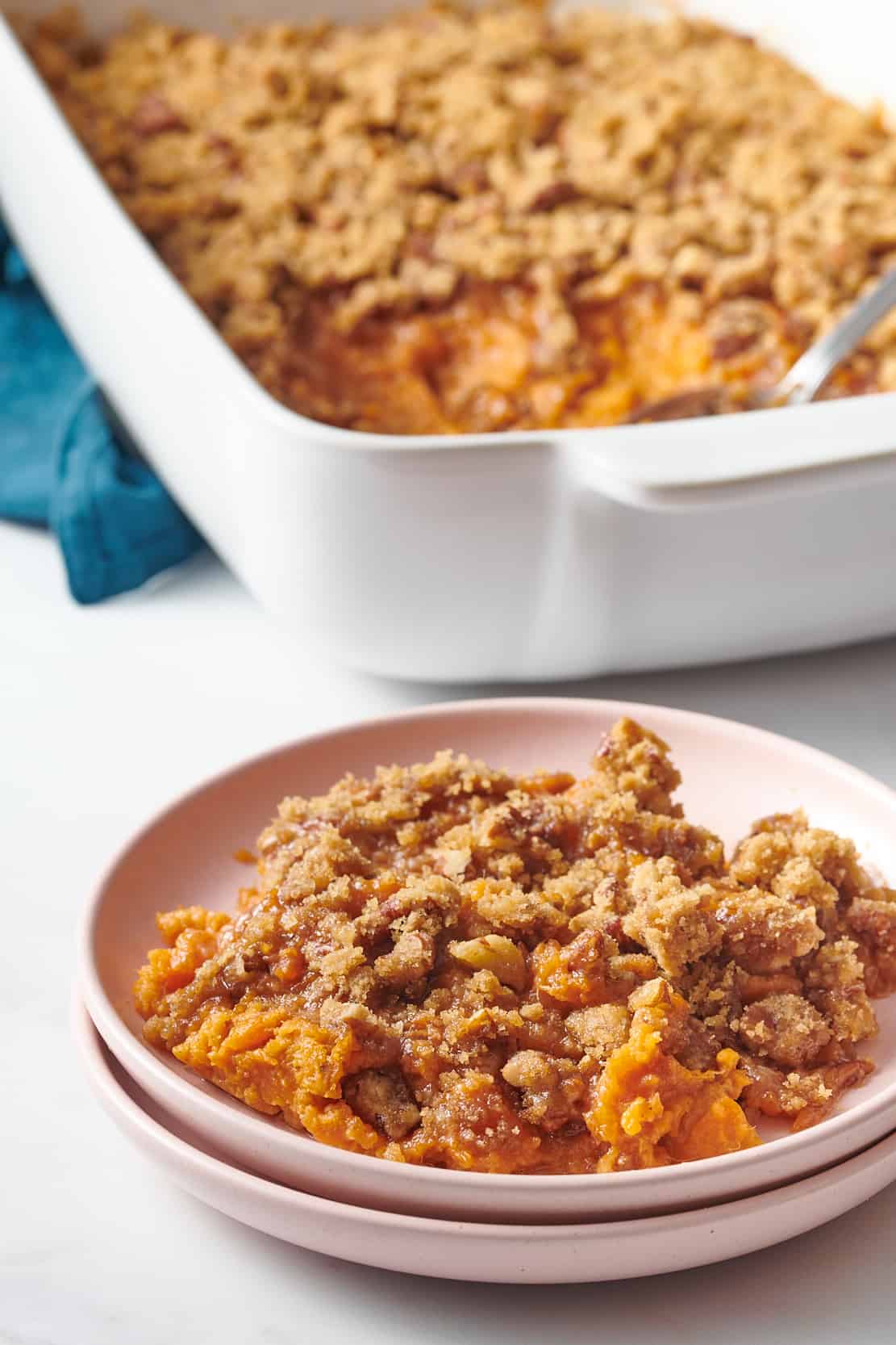 serving of paula deen sweet potato casserole sitting on a stack of two pink plates.