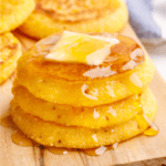 A stack of three cornbread fritters topped with butter and honey.