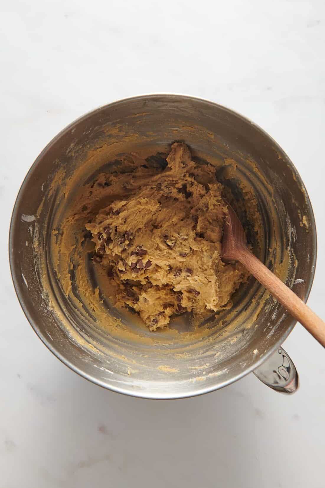 large stainless steel mixing bowl of chocolate chip cookie dough batter. 