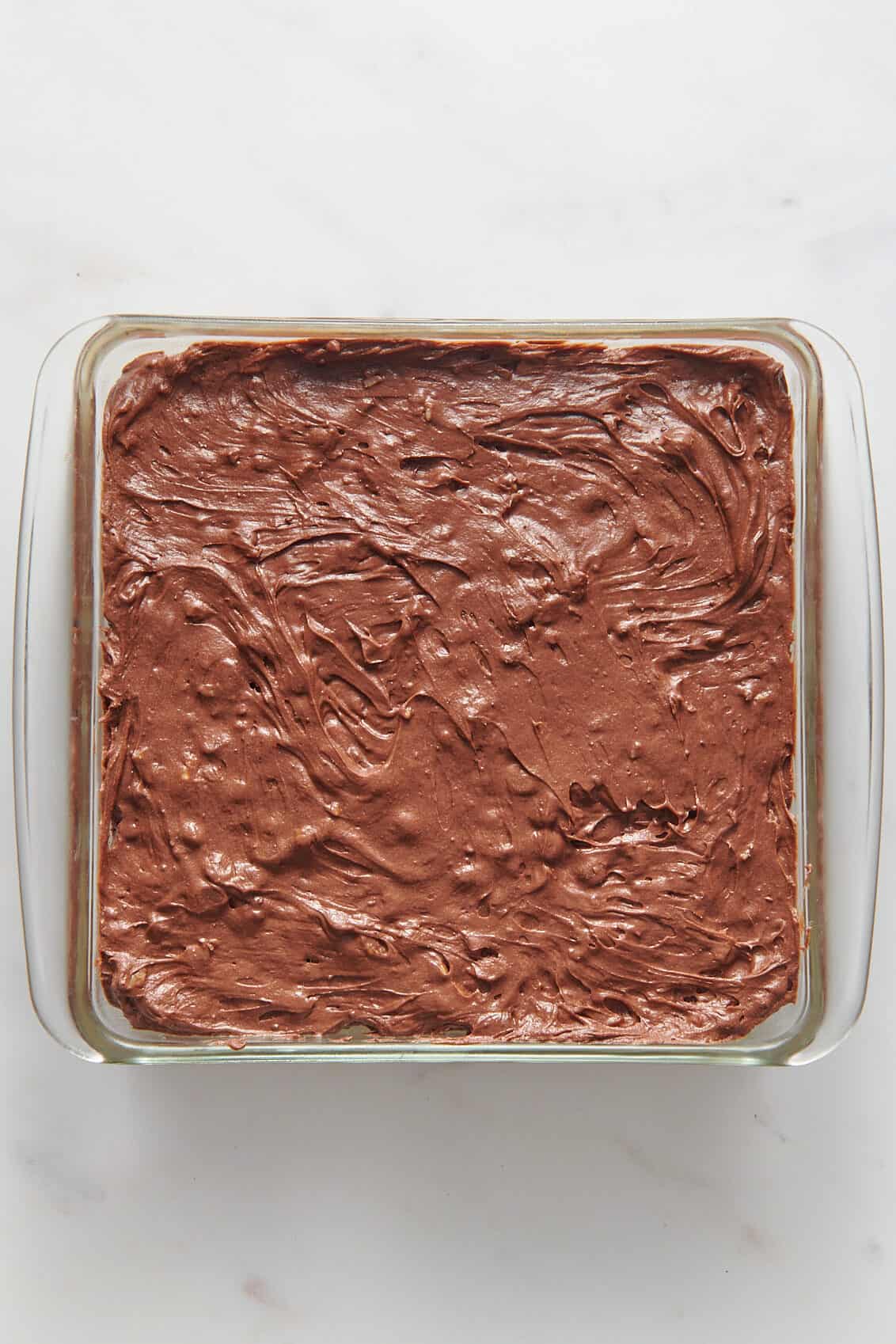 brownie batter layered in a prepared 9x9 glass baking dish.