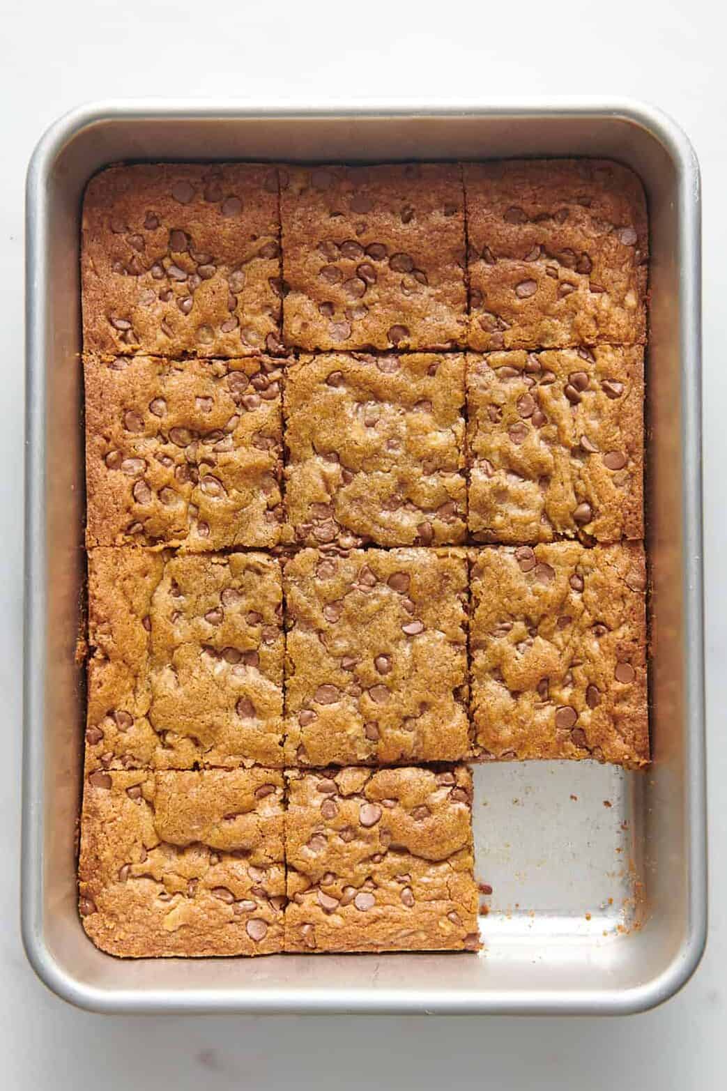 baked toll house chocolate chip cookie bars cut into 12 squares sitting in a 9x13 baking dish.
