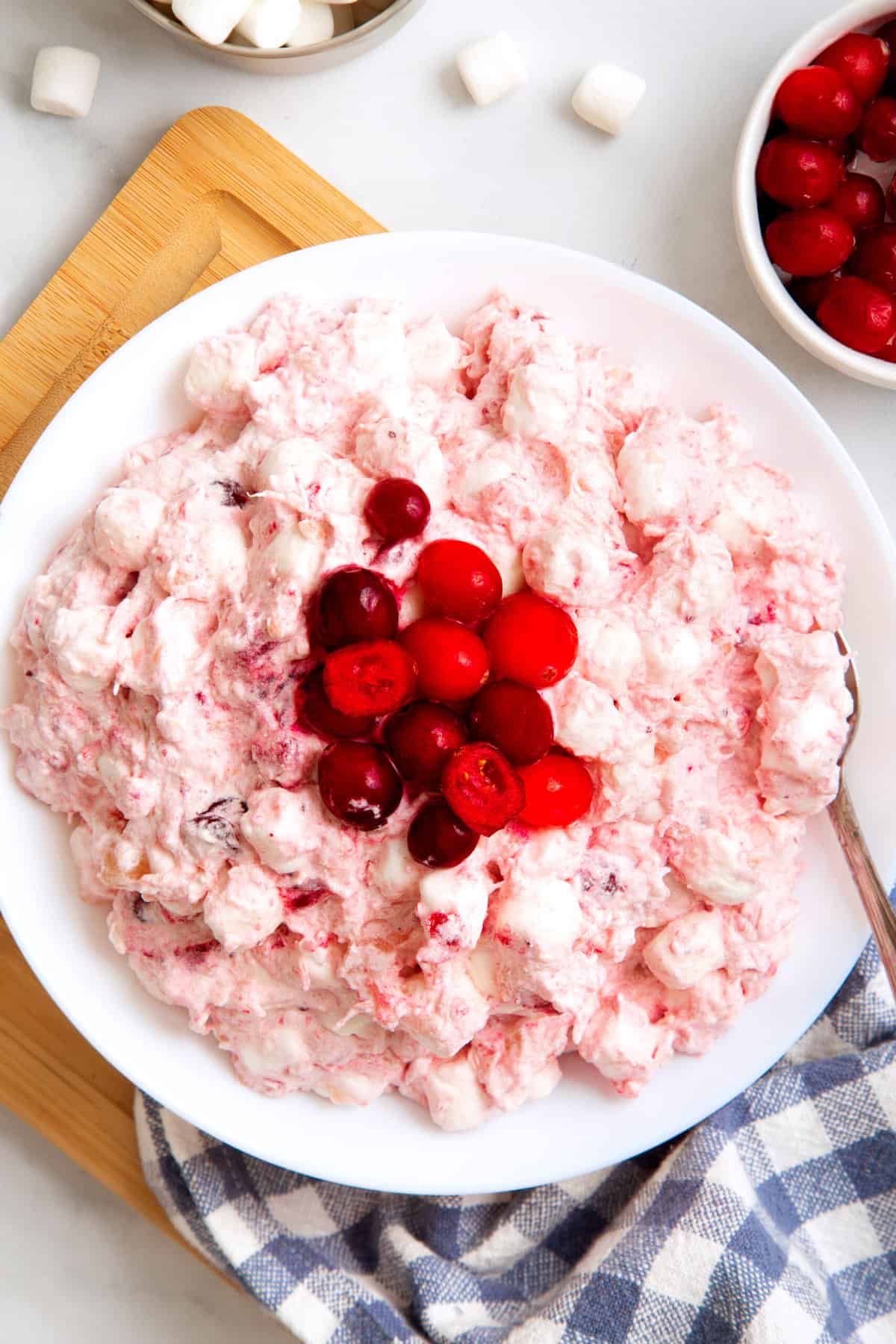 top down image of close up image of cranberry fluff served in a large white bowl topped with cranberries. 