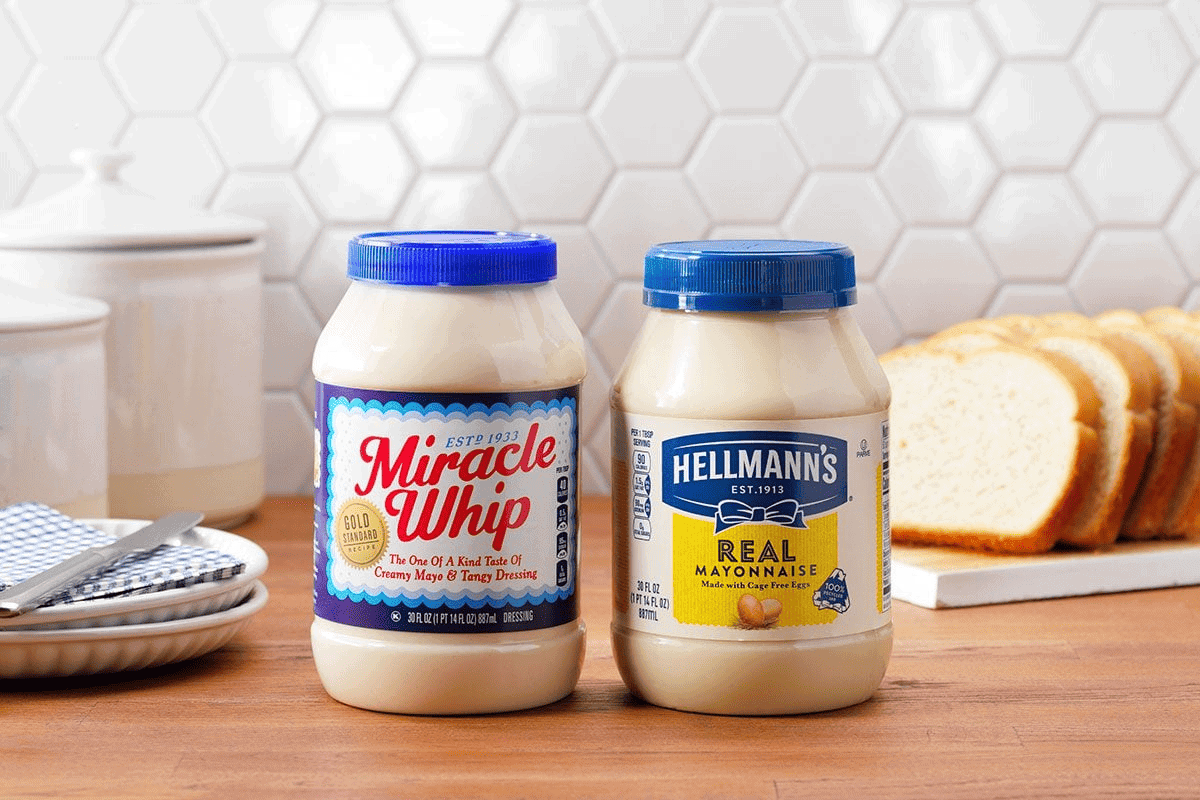 jars of miracle whip and mayo sitting on a wood countertop.
