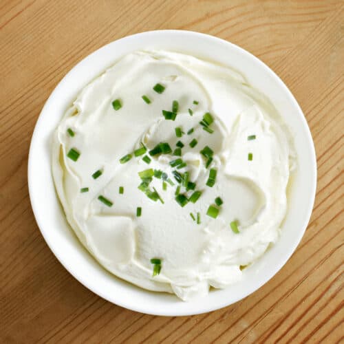 A bowl of homemade sour cream topped with chives.
