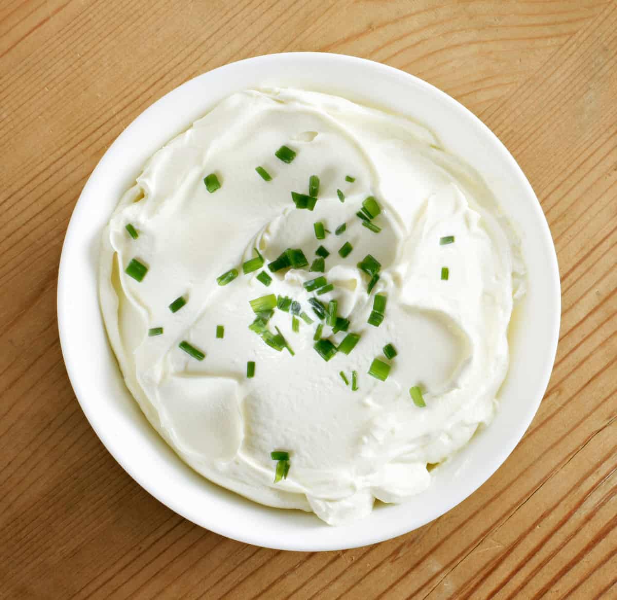 A bowl of homemade sour cream topped with chives.