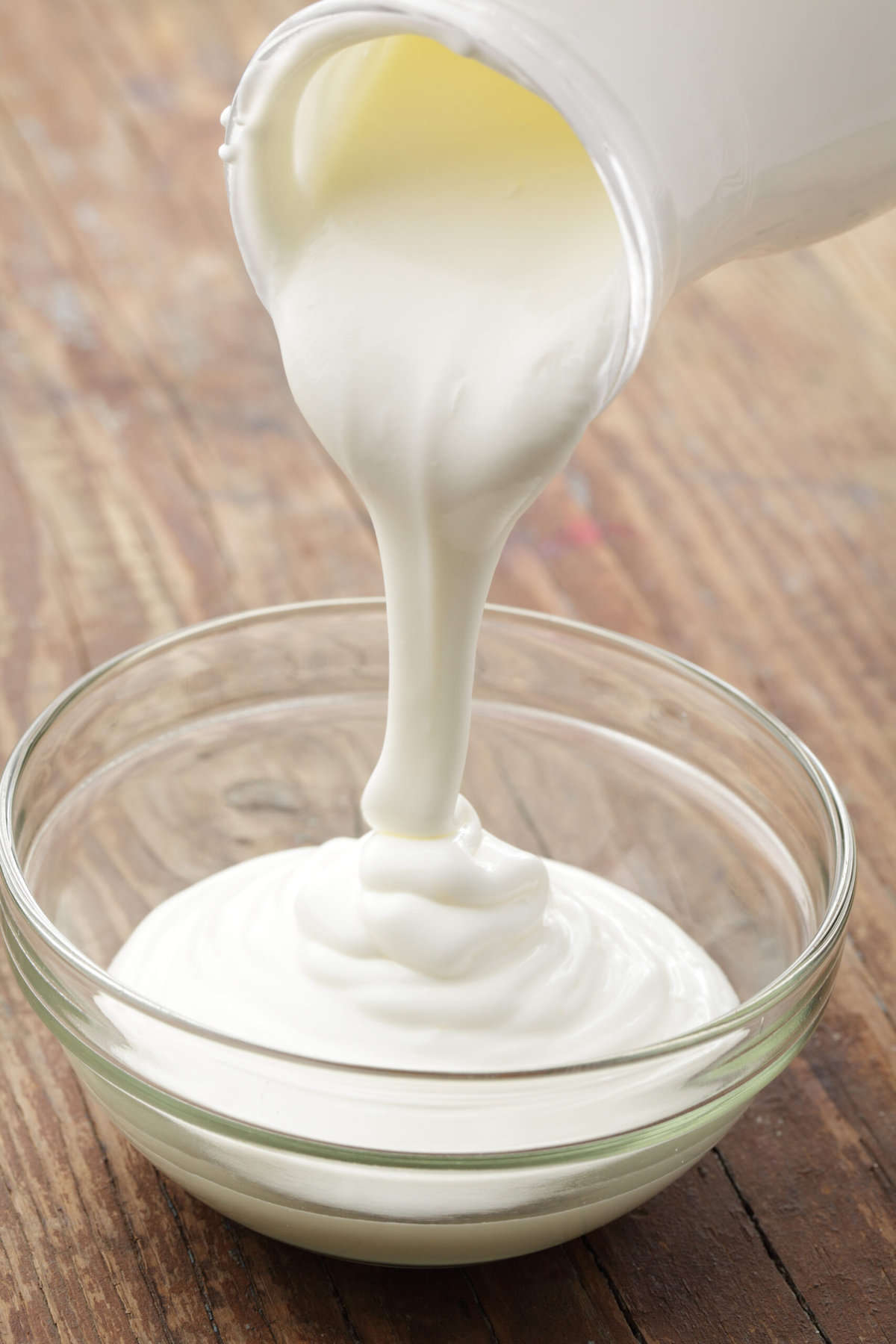 sour cream pouring into a glass bowl. 