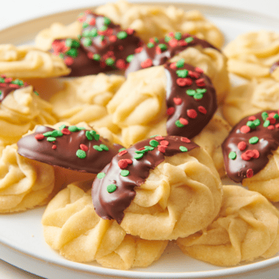 A plate of Christmas butter cookies, some with chocolate and sprinkles.