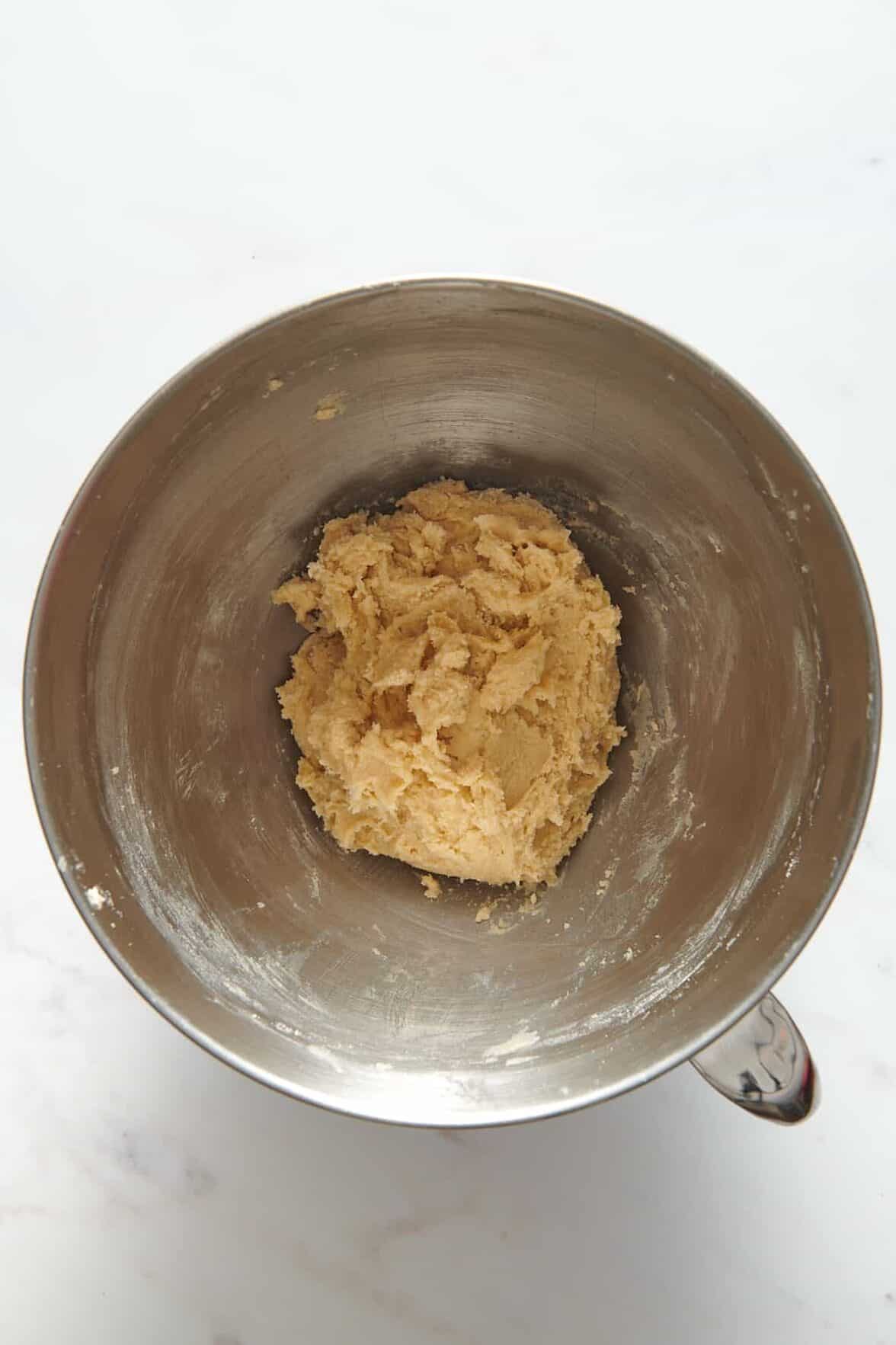 butter cookie dough sitting in a stainless steel mixing bowl.