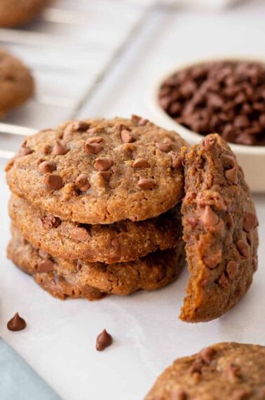 A stack of coffee cookies with one next to it missing a bite.