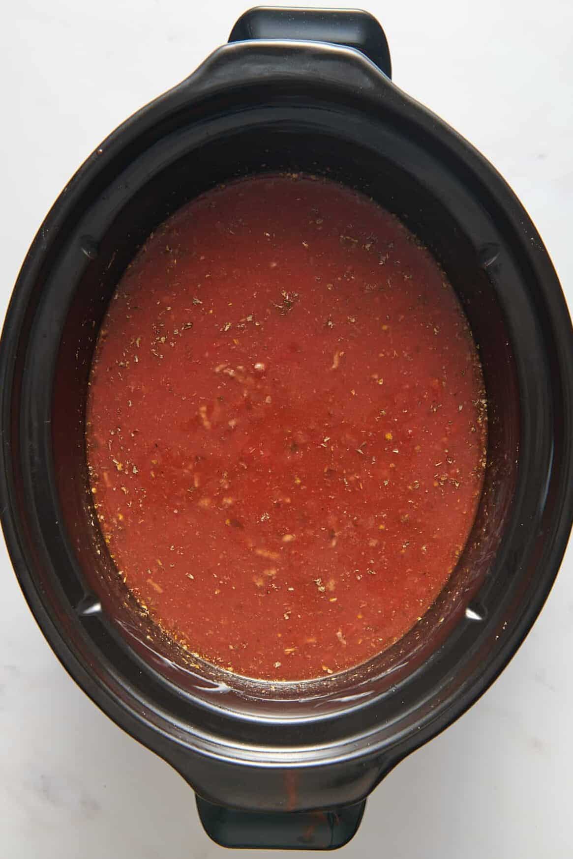 top down image of red pasta sauce in a crock pot. 
