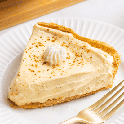 A slice of no bake egg nog pie topped with whipped cream on a plate.