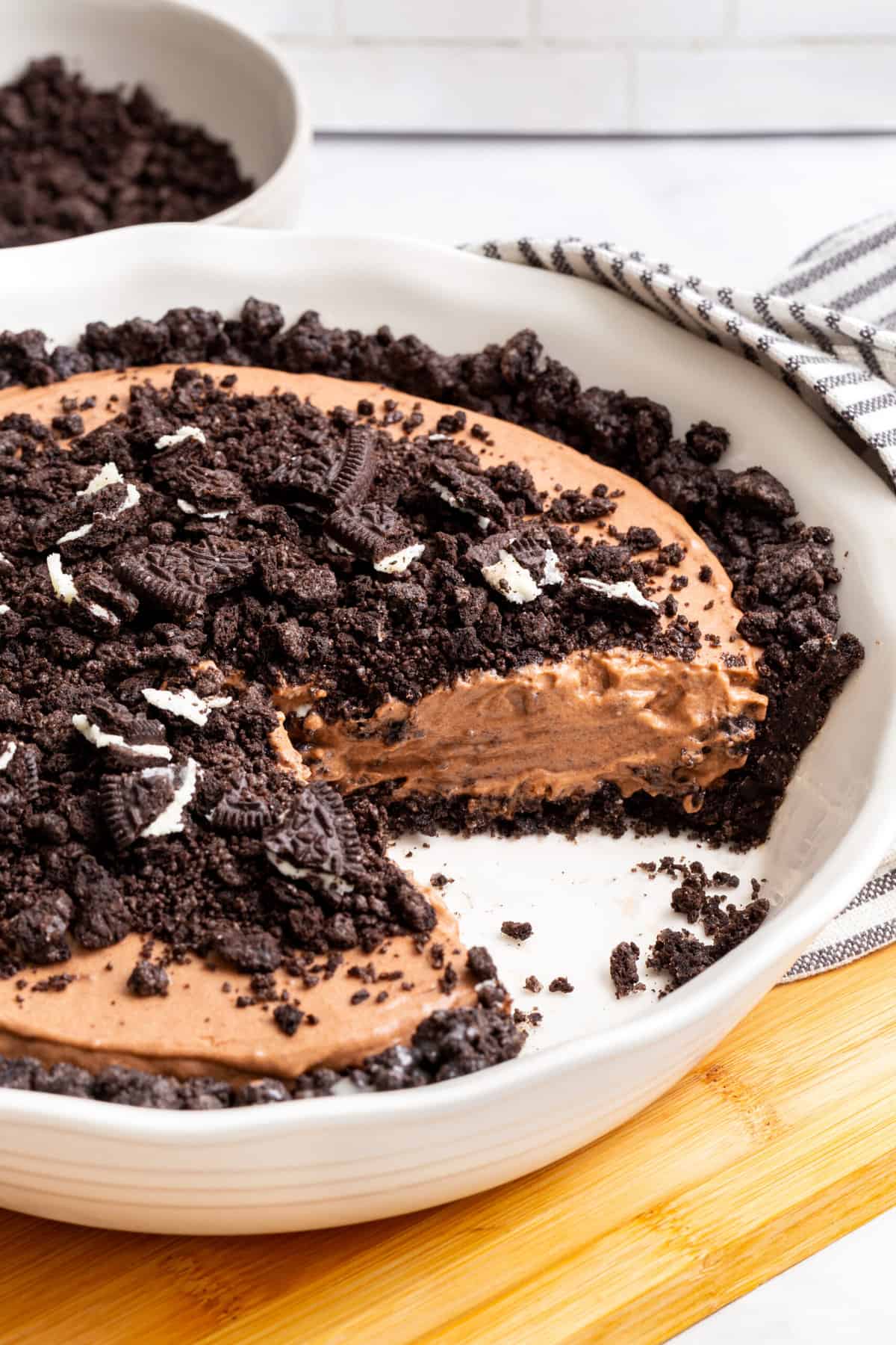 close up image of the cross section of oreo dirt pie sitting in a ceramic pie dish. 