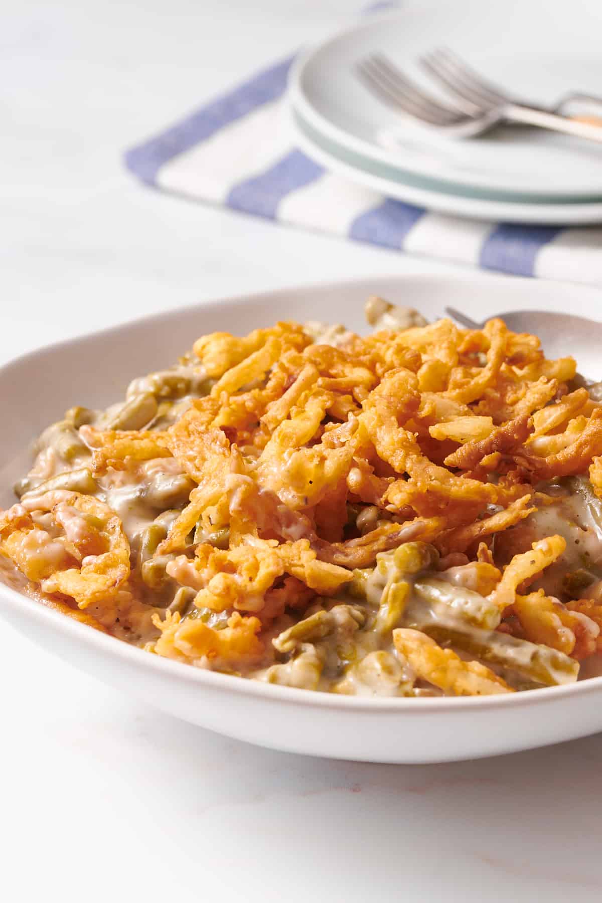 close up image of a serving of slow cooker green bean casserole topped with french fried onions. 