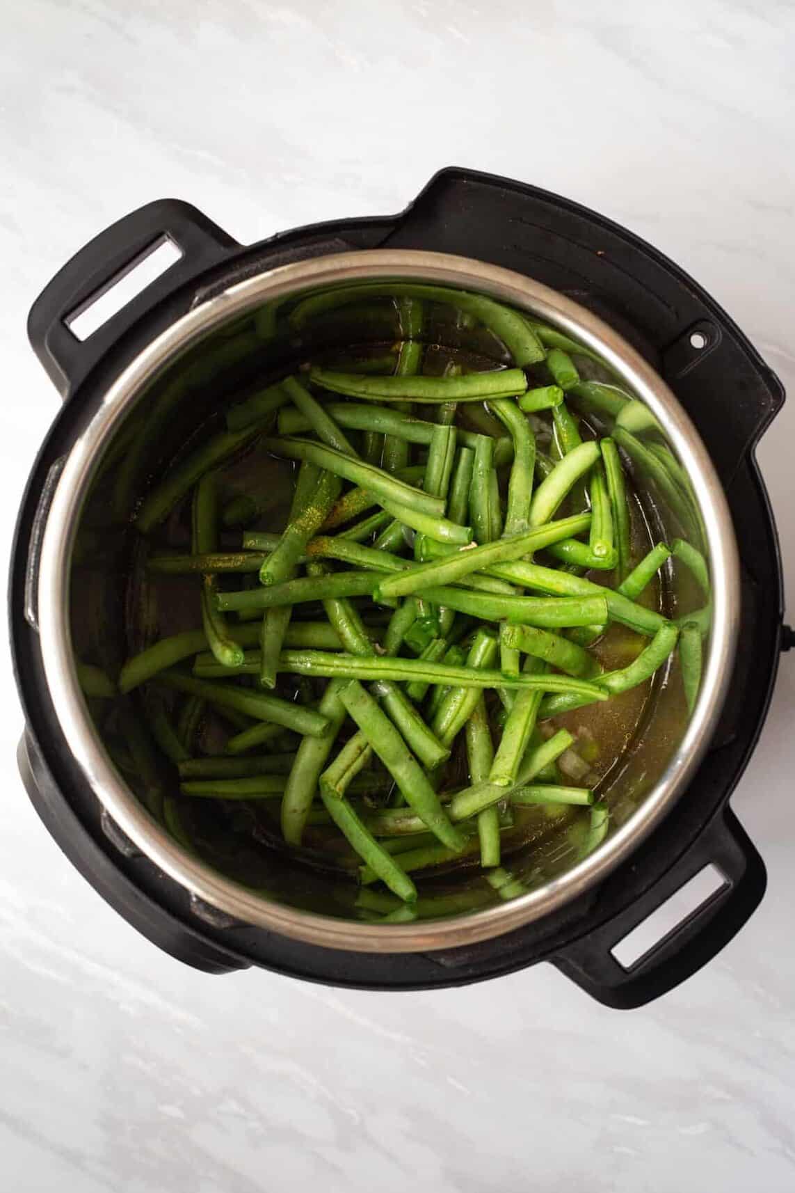 instant pot with green beans sitting in broth.