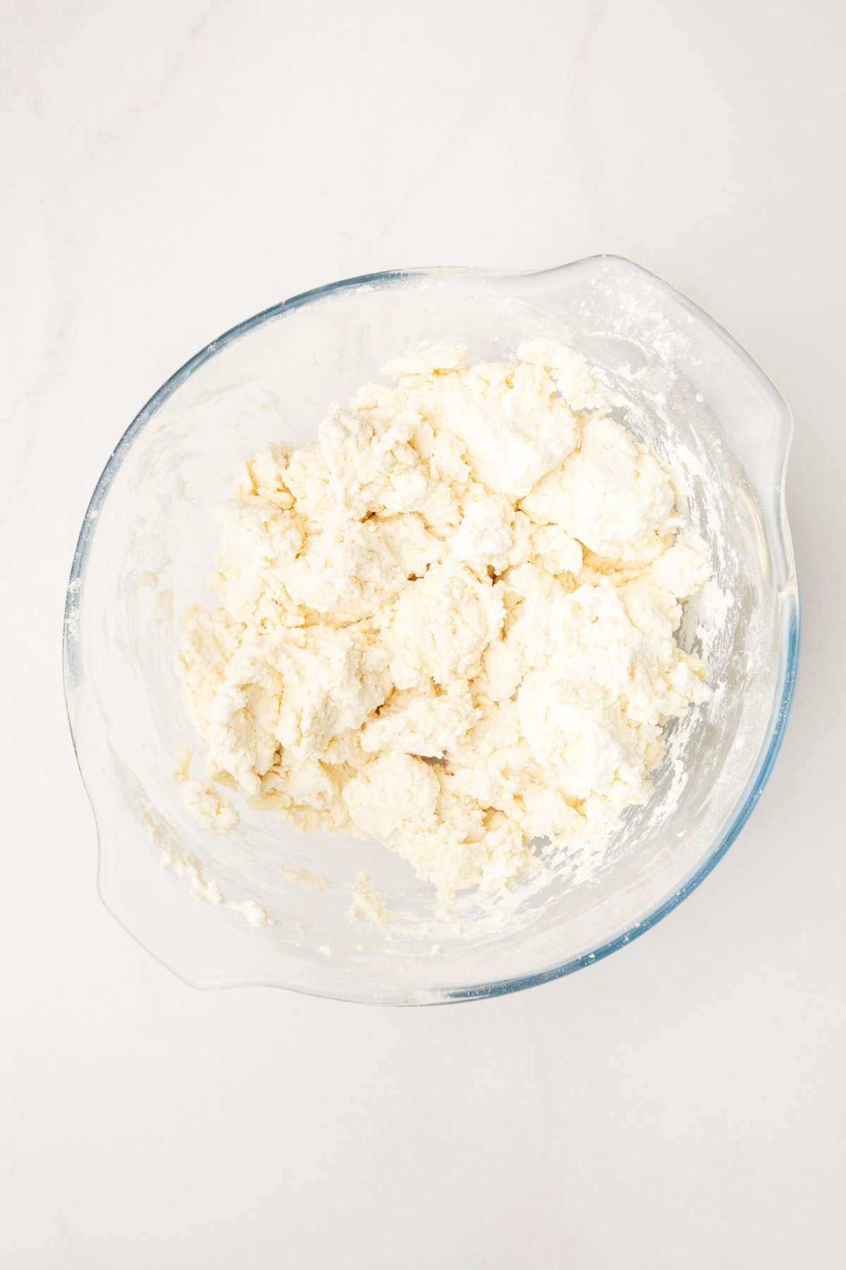 large glass mixing bowl with all-purpose flour mixed into butter.