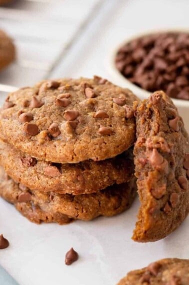 A stack of coffee cookies with one next to it missing a bite.