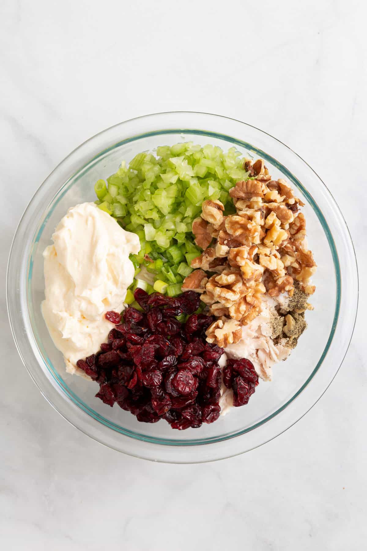 chicken salad ingredients unmixed in a large glass bowl. 