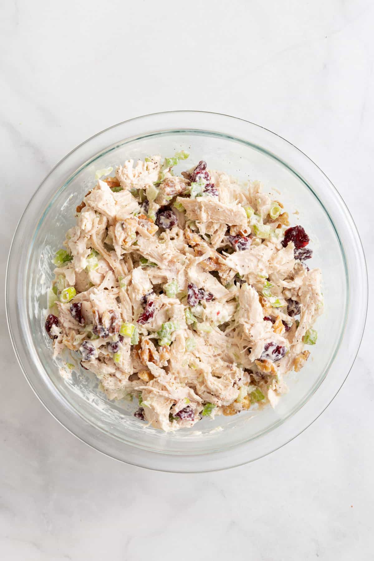 chicken salad ingredients well combined in a large glass bowl. 