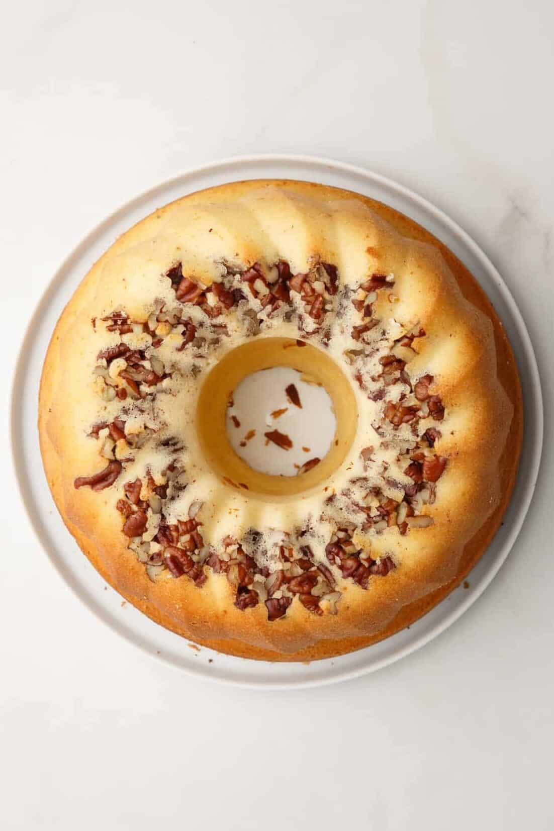 cake mix run bundt cake with pecans sitting on a white round plate.
