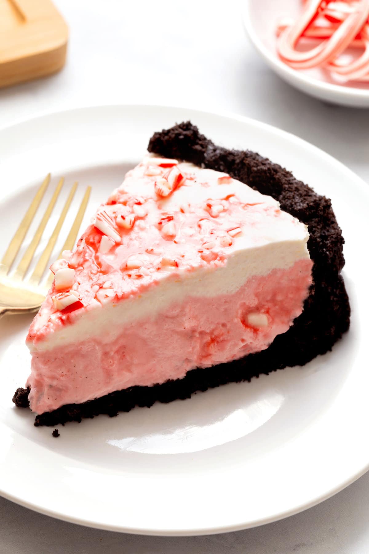 slice of candy cane pie served on a white round plate. 