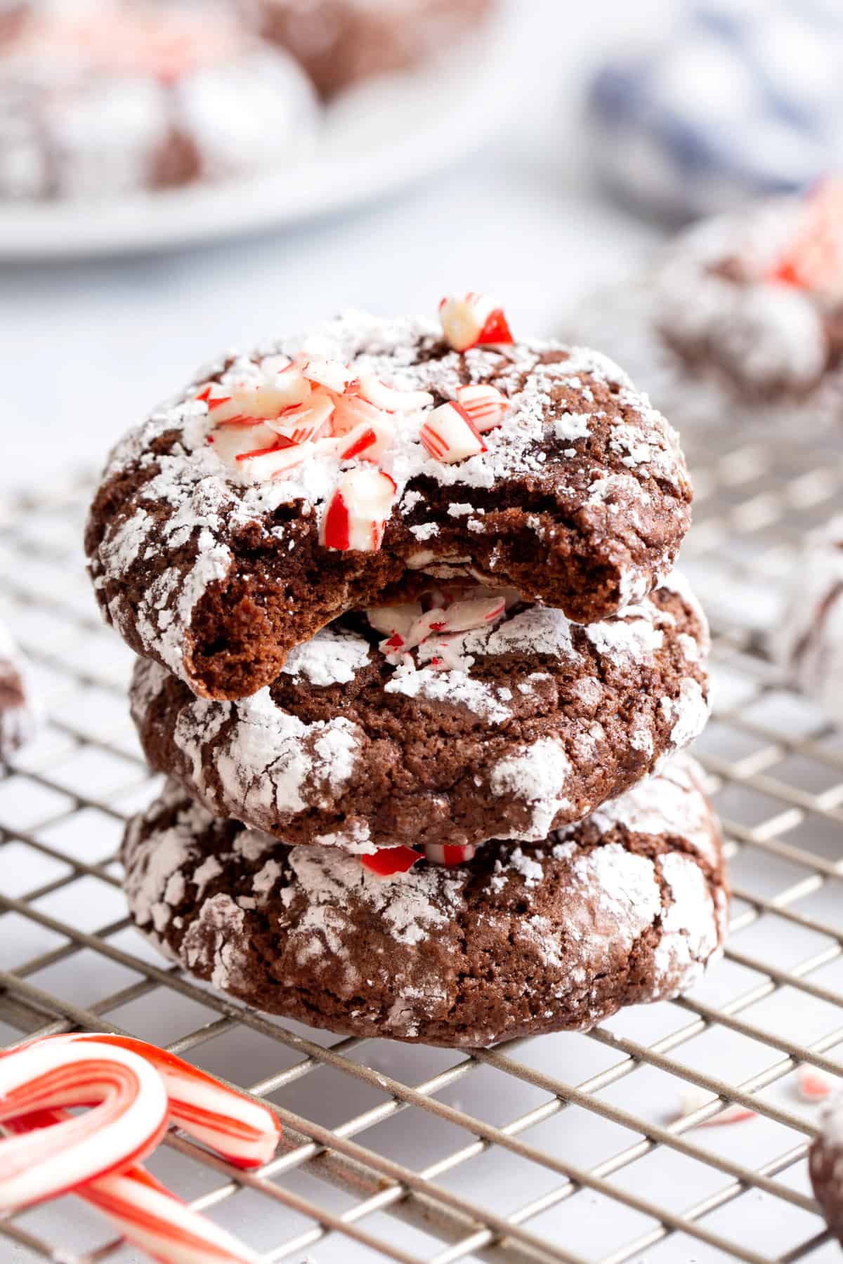 stack of three chocolate mint crinkle cookies sitting on a wire cooling rack. 