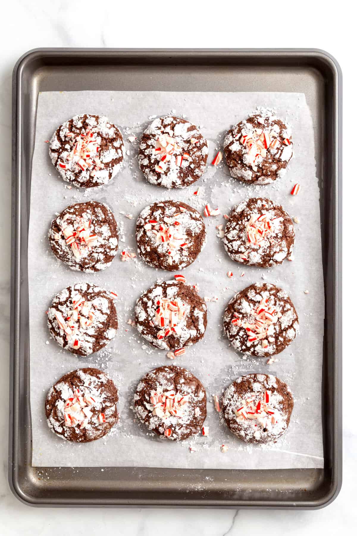 parchment-lined baking sheet with twelve chocolate mint crinkle cookies. 