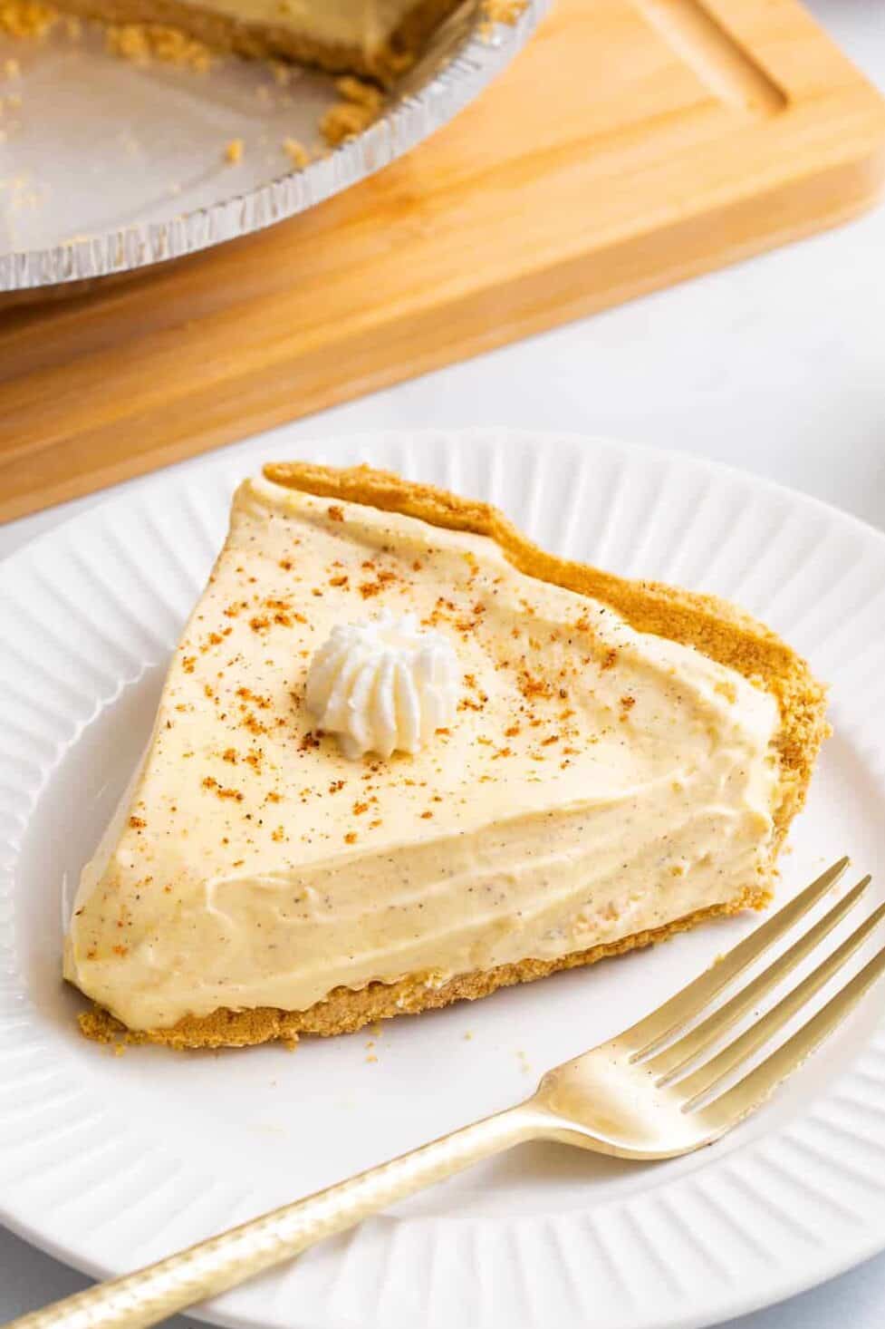 close up image of a slice of no bake egg nog pie served on a white round plate. 