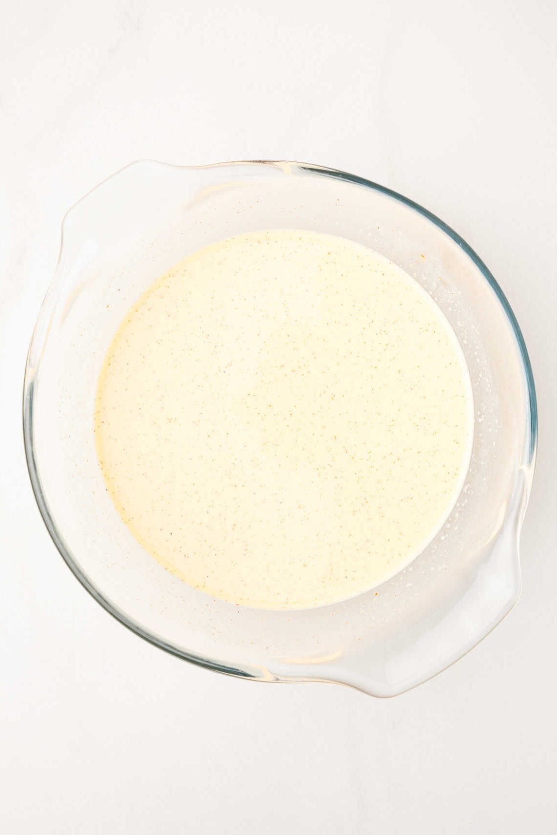 eggs, cream, milk combined in a large glass mixing bowl. 
