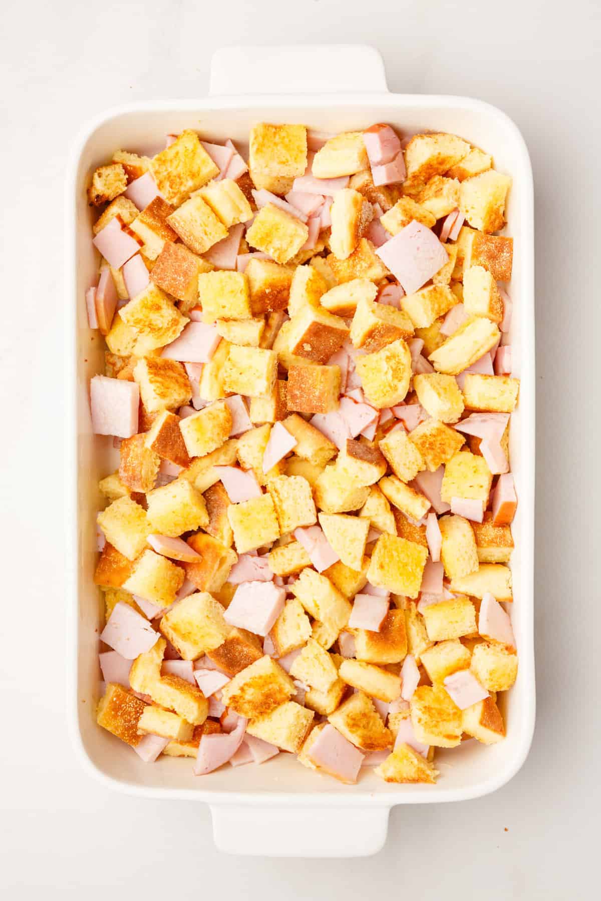 chopped canadian bacon pieces and  cubed english muffin pieces in a 9x13 casserole dish. 