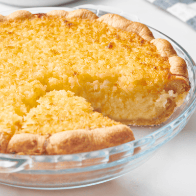 An old-fashioned coconut pie with a slice missing.