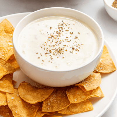 A bowl of Velveeta queso blanco recipe surrounded by tortilla chips.