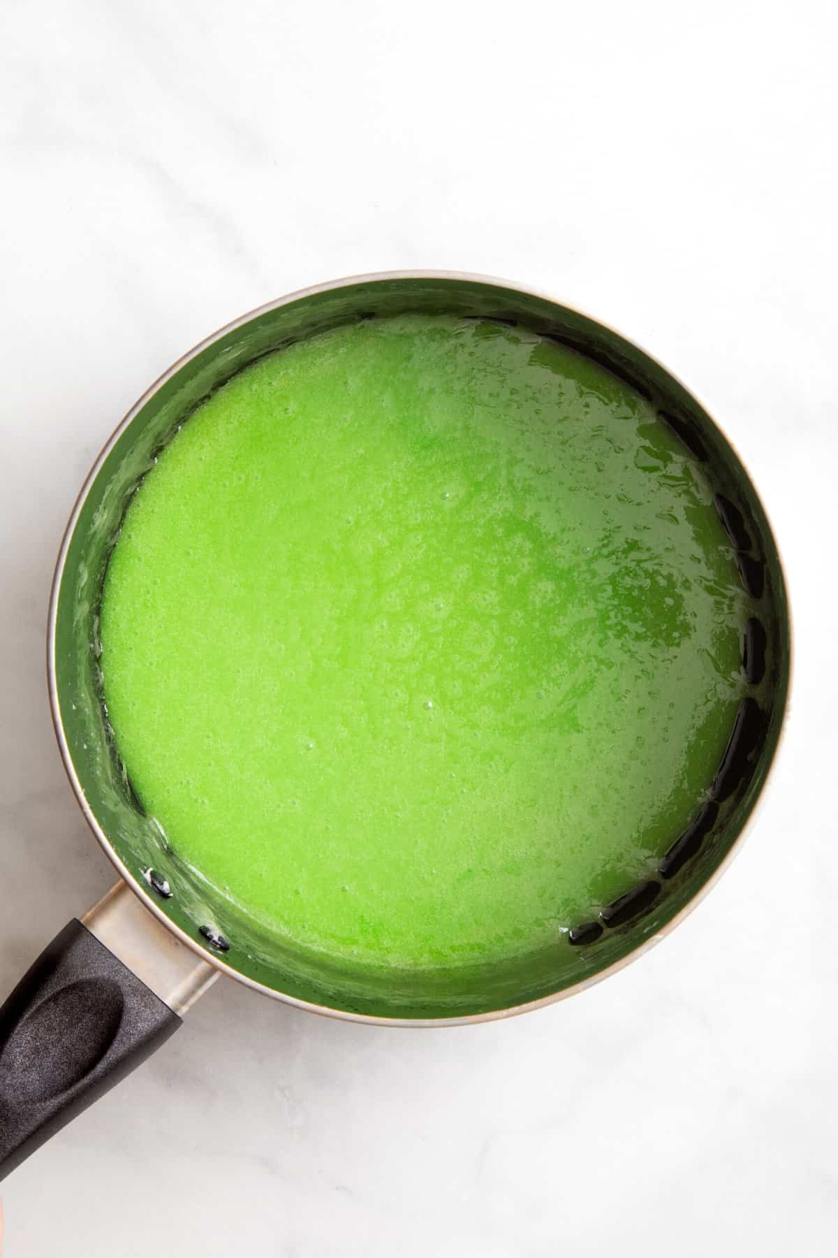 green food coloring with melted butter and marshmallows in a sauce pan. 