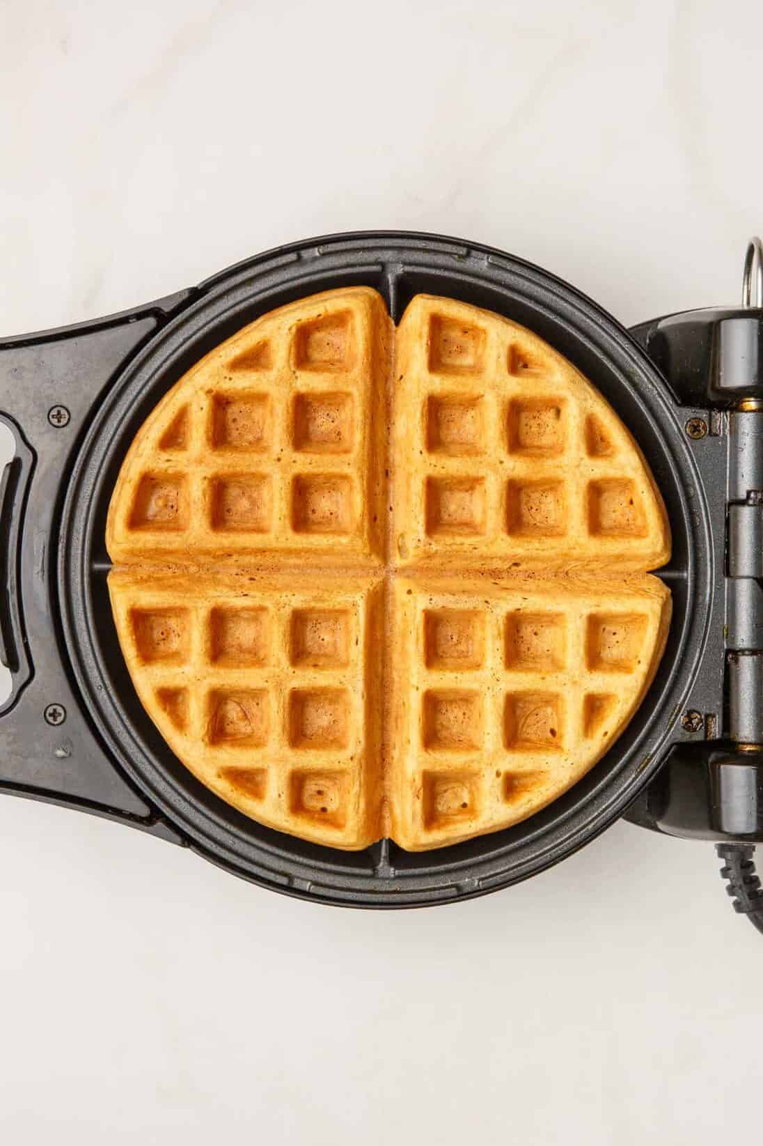 top down image of a buttermilk waffle sitting in a waffle iron. 