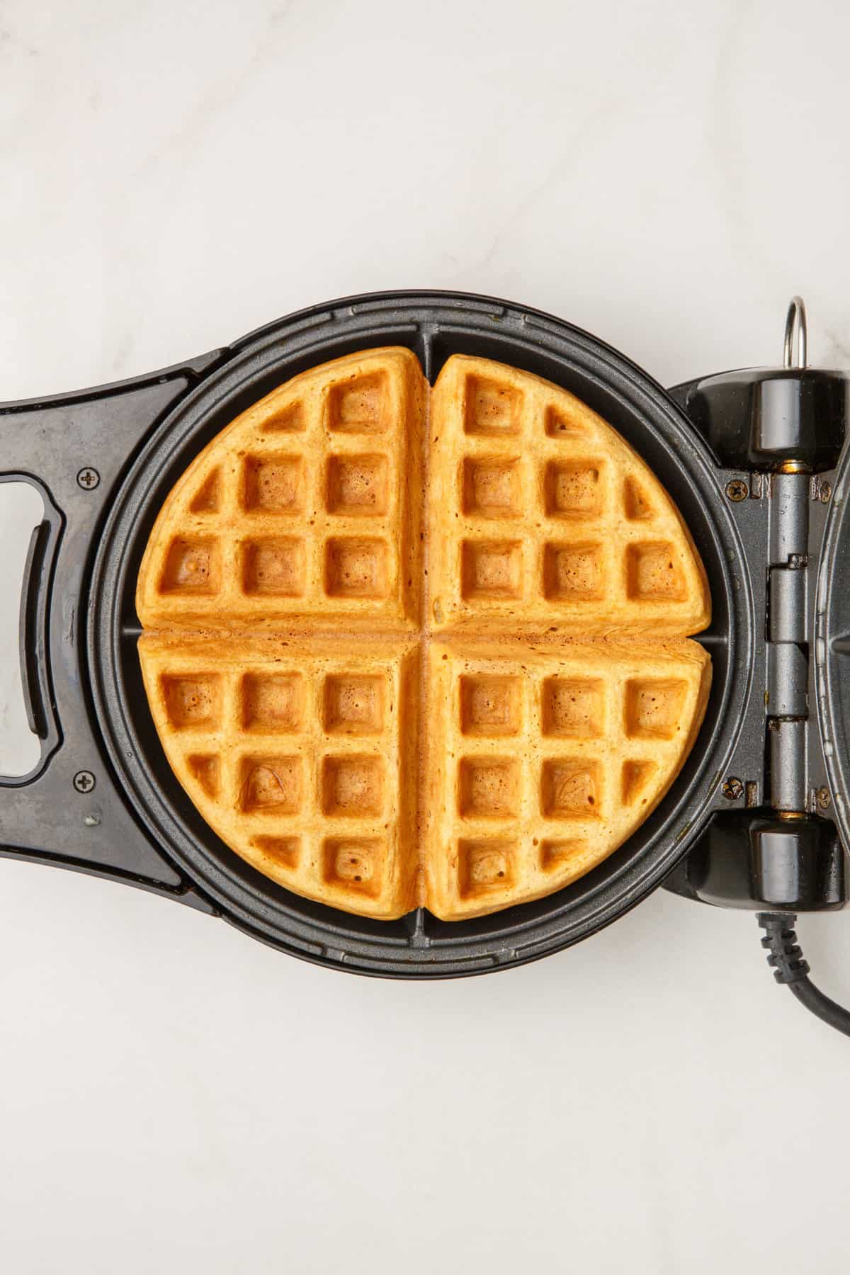 A waffle being cooked in a waffle iron. 