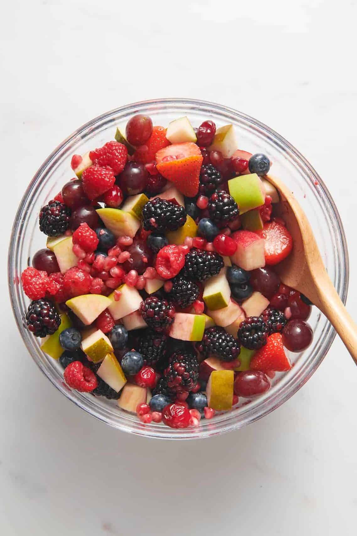 top down image of christmas fruit salad served in a large glass bowl. 