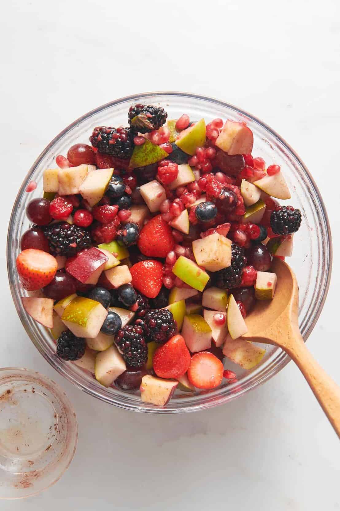 top down image of christmas fruit salad served in a large glass bowl. 