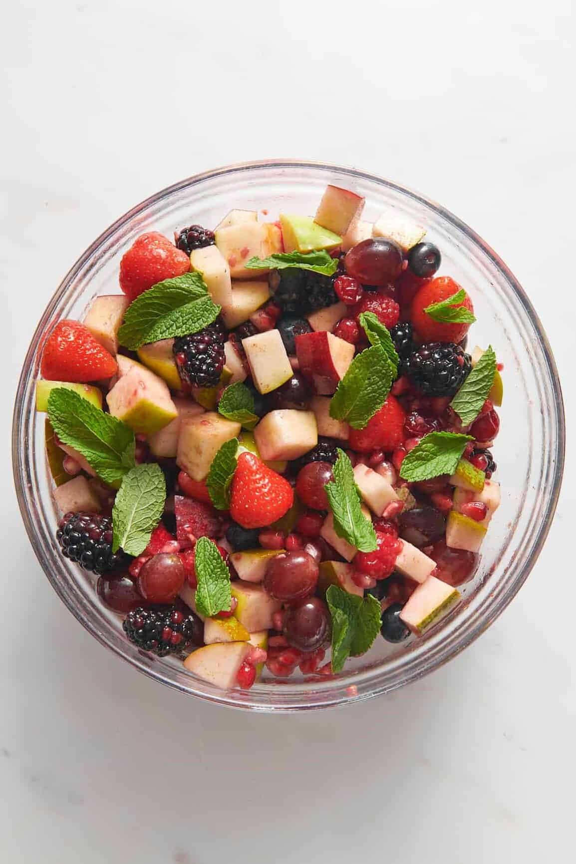 top down image of christmas fruit salad served in a large glass bowl. 