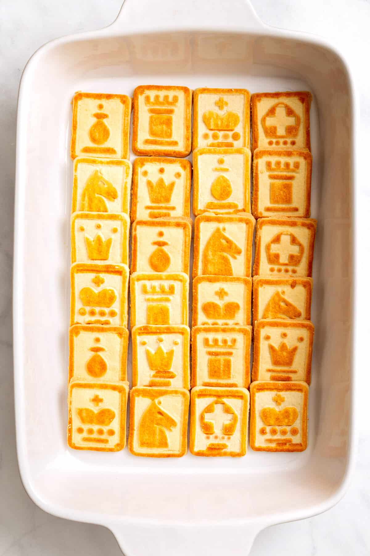 top down image of chessman cookies arranged in an even layer at the bottom of a 9x13 inch casserole dish.