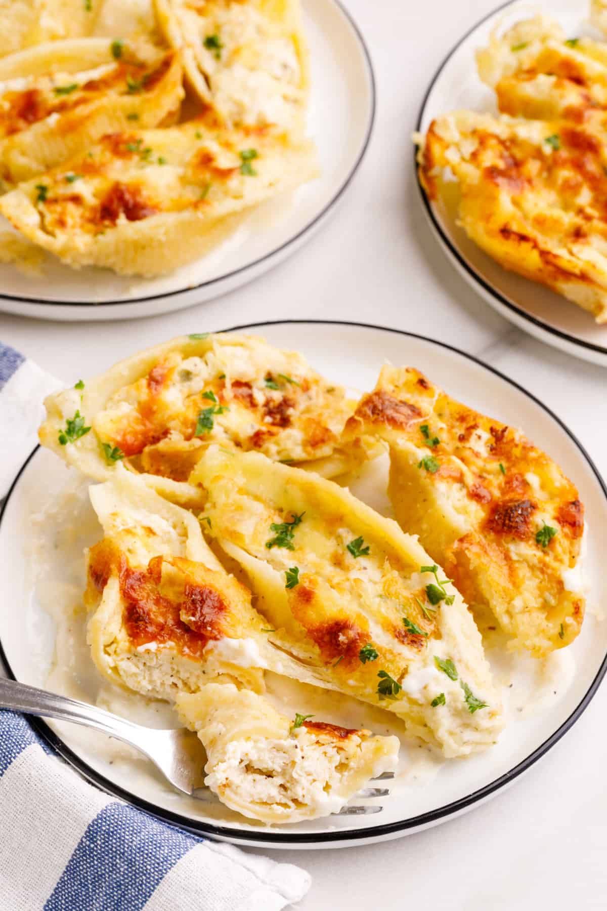 serving of chicken alfredo stuffed shells sitting on a white round plate. 