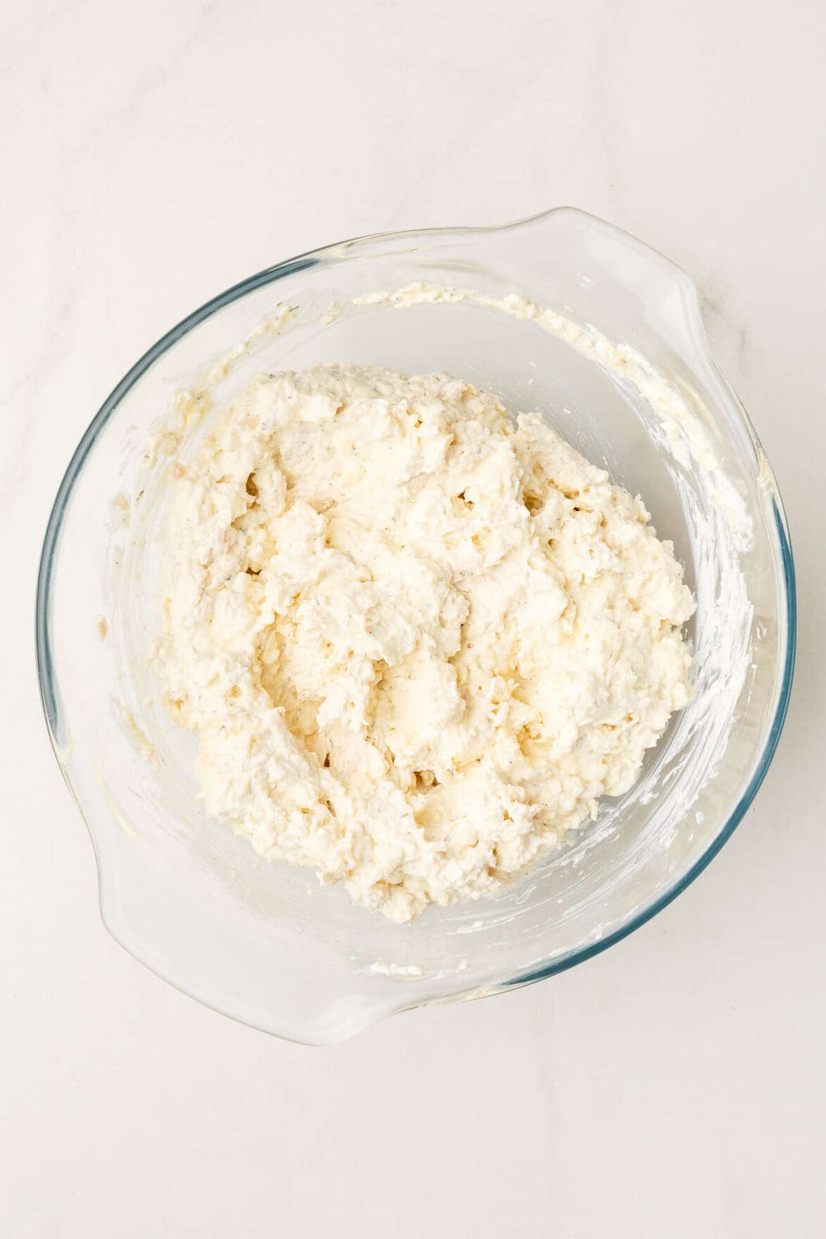 top down image of chicken alfredo filling for chicken alfredo stuffed shells sitting in a large glass bowl. 