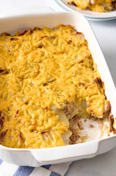 Hamburger and potato casserole in a baking dish with a serving missing.