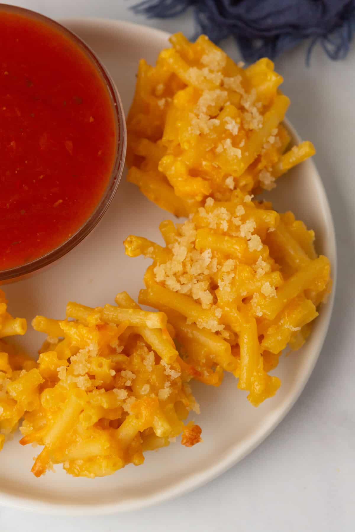 Mac and cheese bites on a plate next to a bowl of dip.