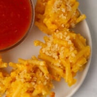 Mac and cheese bites on a plate next to a bowl of dip.