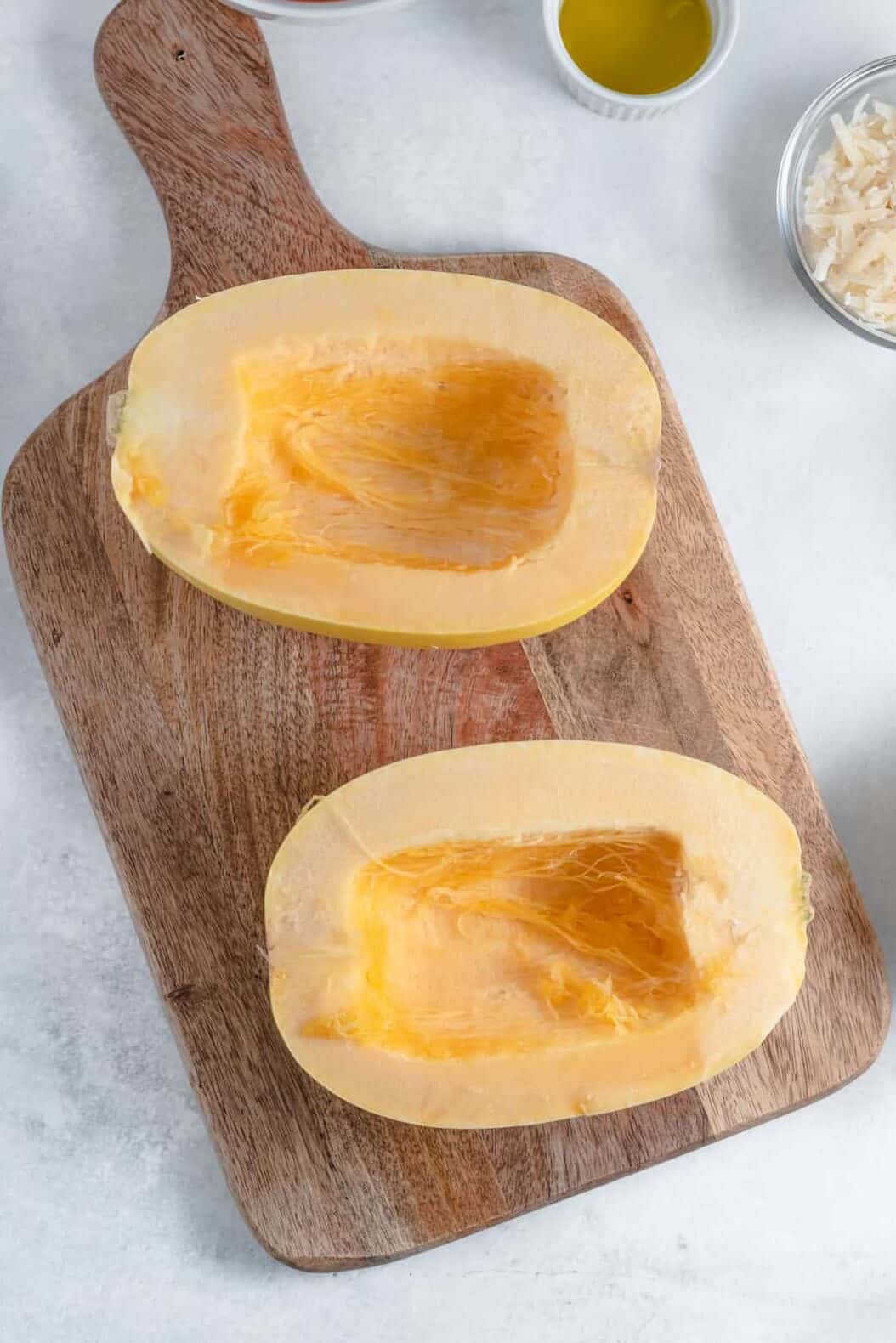 top down image of squash cut in half and cored sitting on a wood cutting board.