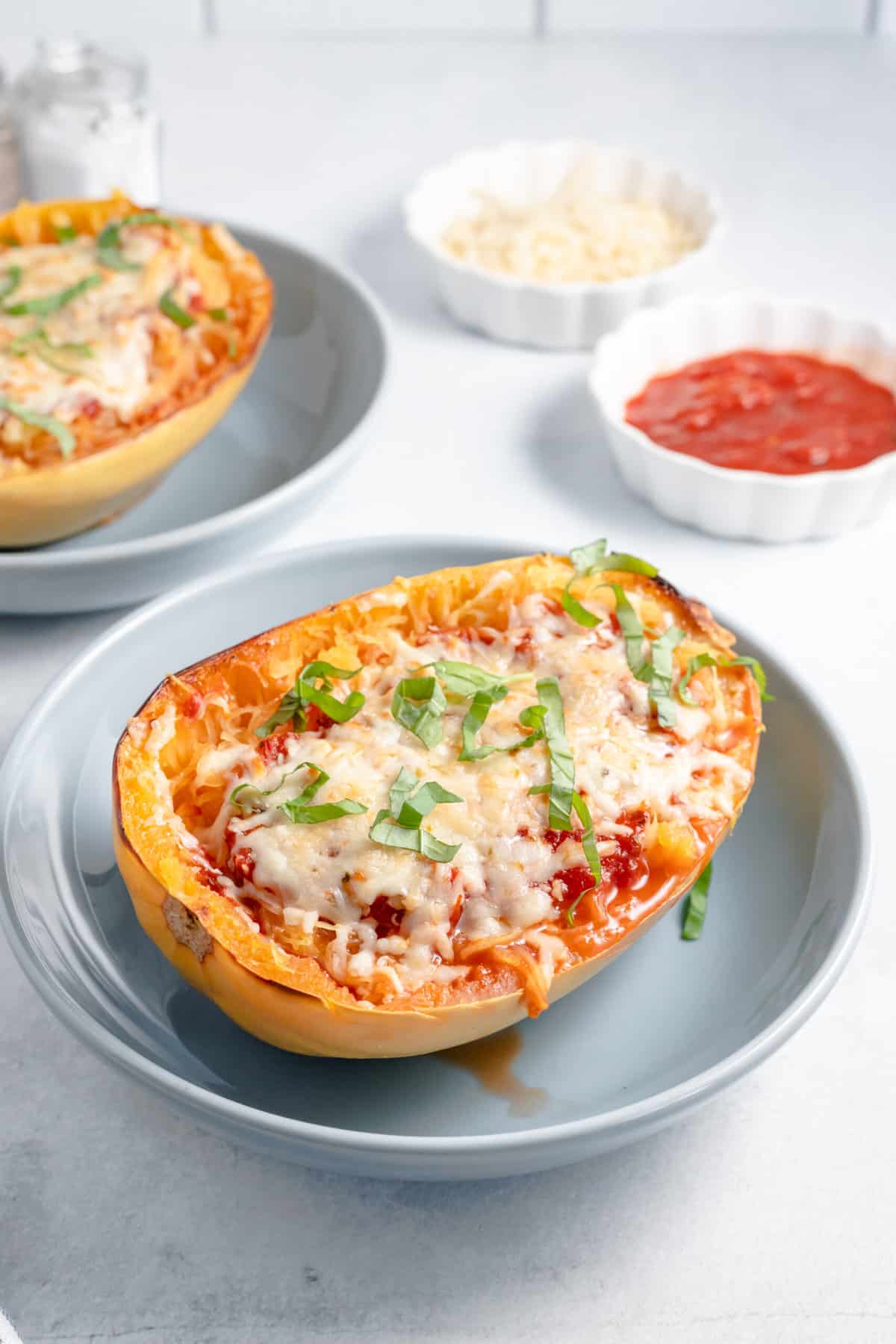 close up image of a serving of stuffed lasagna spaghetti squash sitting in a shallow grey plate. 