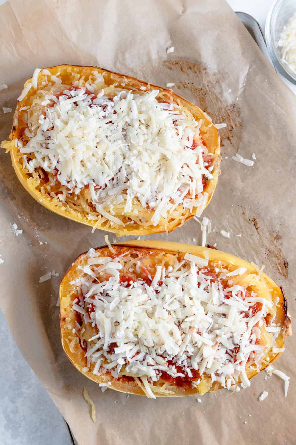 top down image of stuffed lasagna spaghetti squash sitting on a parchment lined baking sheet.