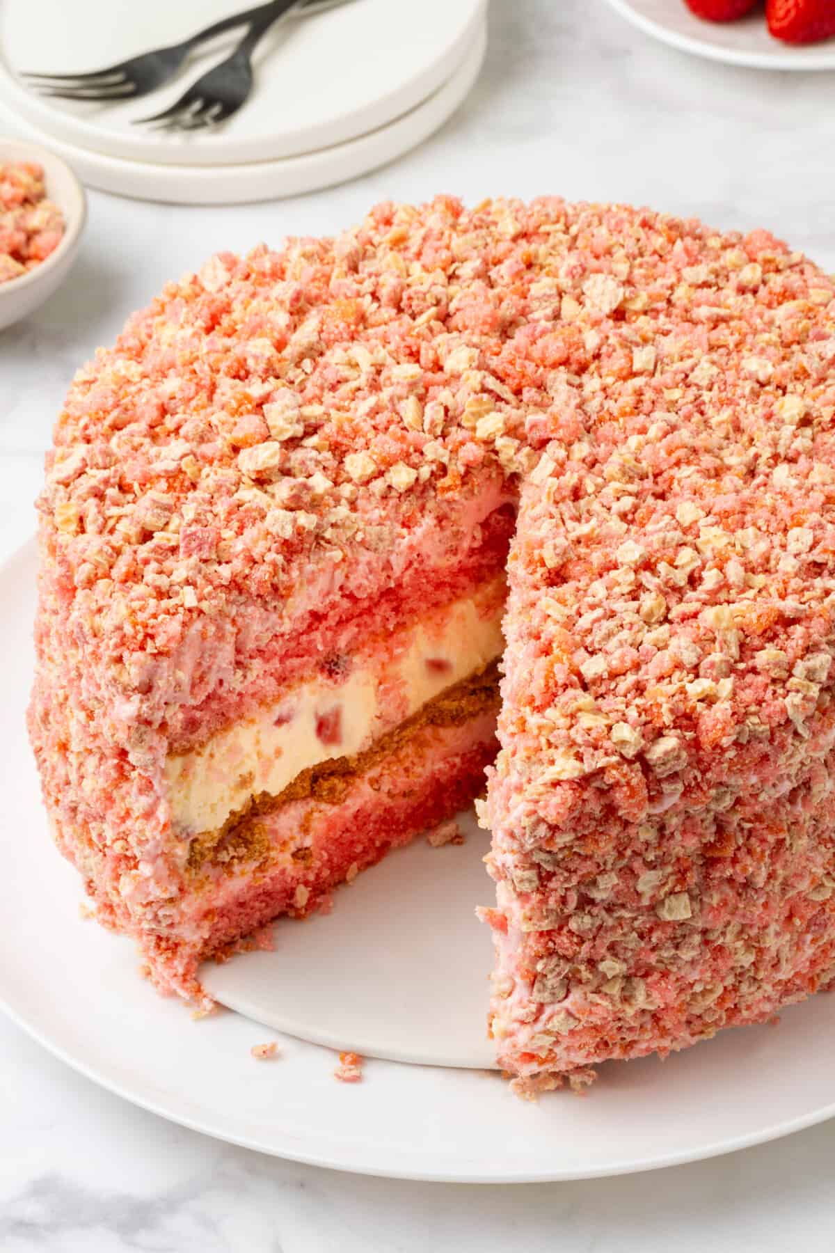 Round strawberry cake with slice removed showing layers.